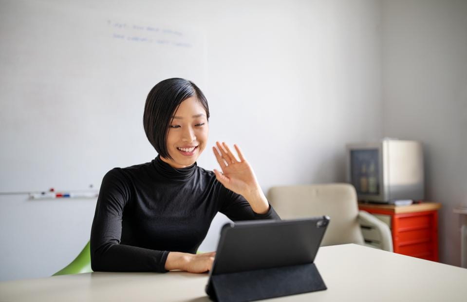 woman waving at Zoom call on tablet