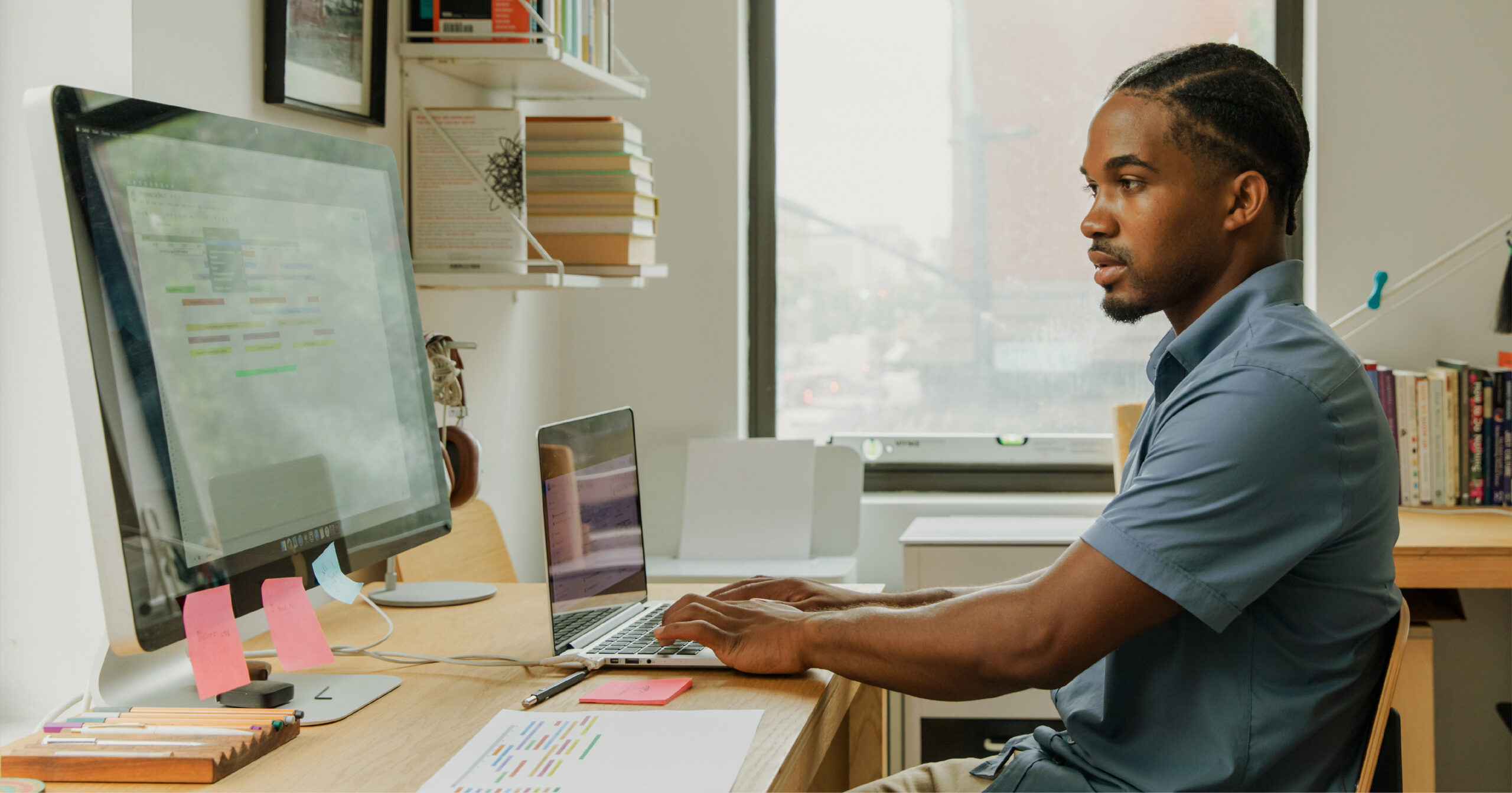 Marketing designer at his desk working on a graphic design project with two computers.