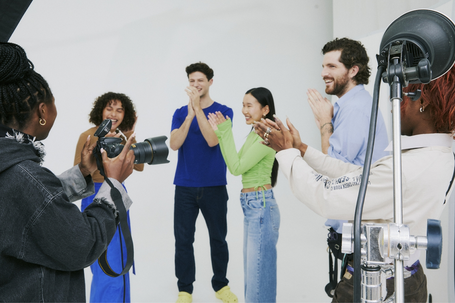 A photographer captures four people standing together and smiling in a studio, with lighting equipment in view—perfect for creating branded video content that showcases authentic connections.