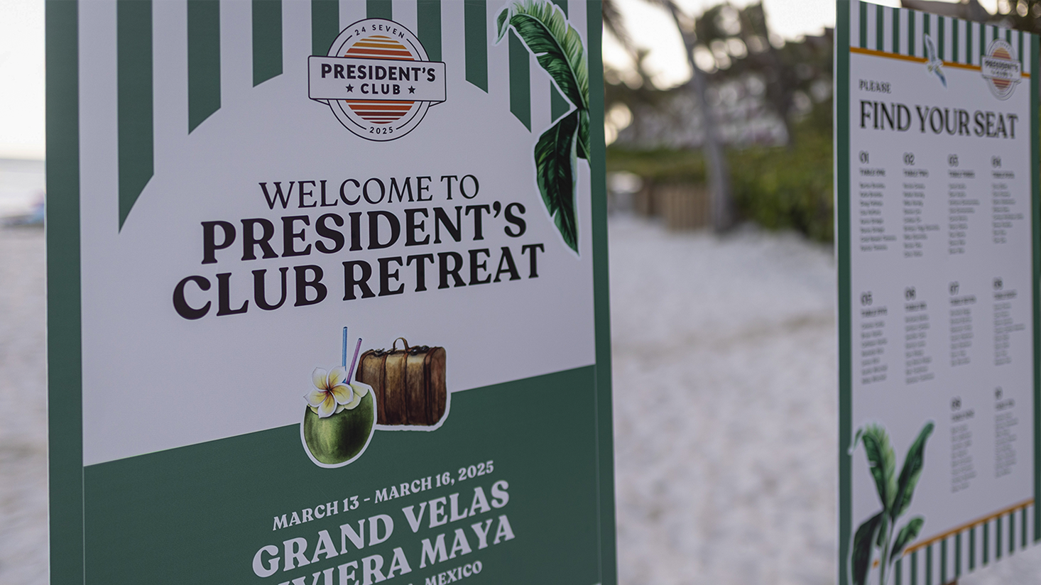 Two signs on a sandy beach welcome President's Club attendees to the 24 Seven President's Club Retreat at Grand Velas Riviera Maya in March 2025, capturing excellence and providing a seating chart.