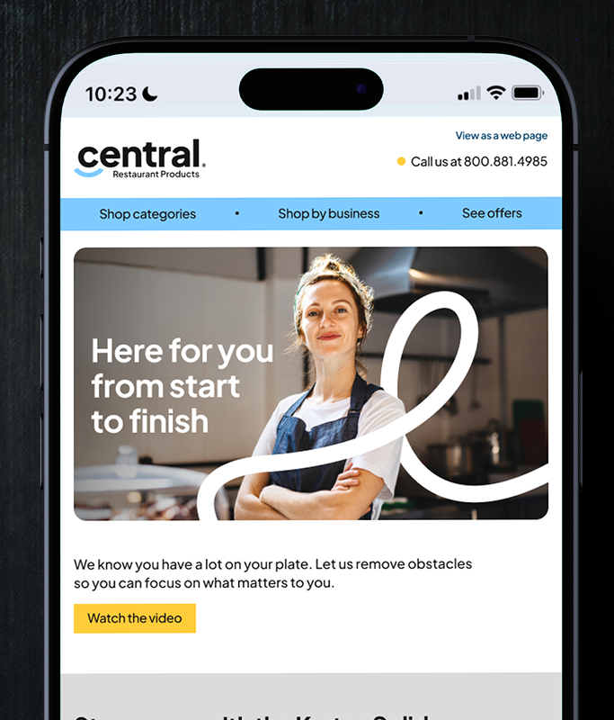 A woman wearing an apron stands confidently in a commercial kitchen, highlighted on the Central Restaurant Products website displayed on a smartphone, emphasizing the human side of finance much like NerdWallet connects users to financial insights.