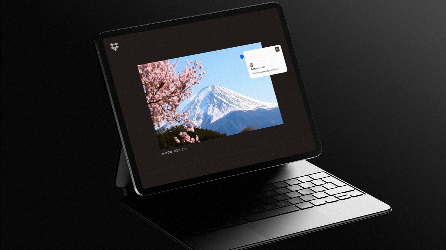 A tablet with a keyboard displays a photo of a snowy mountain and cherry blossoms on its screen, with a small popup menu in the upper right corner—offering clarity amid creative chaos, much like Dropbox Dash.