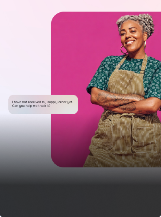 A woman with gray hair and tattoos, wearing a green shirt and striped apron, stands smiling in front of a pink background. A text box asks about tracking a missing supply order using Lua AI or another personal artificial intelligence.