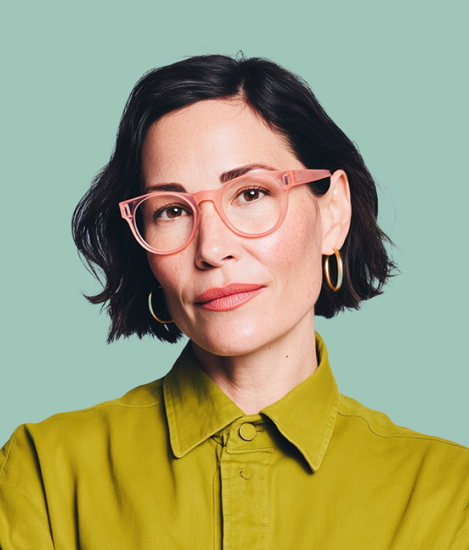 Woman with short dark hair, wearing pink eyeglasses, gold hoop earrings, and a green collared shirt poses against a plain light teal background, embodying the innovative spirit of Lua AI.