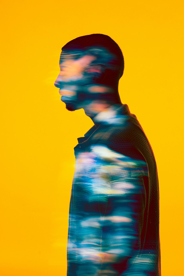 A man in profile stands against a yellow background. His silhouette, enhanced by a colorful, blurred light effect, reflects the creative possibilities enabled by Generative AI.