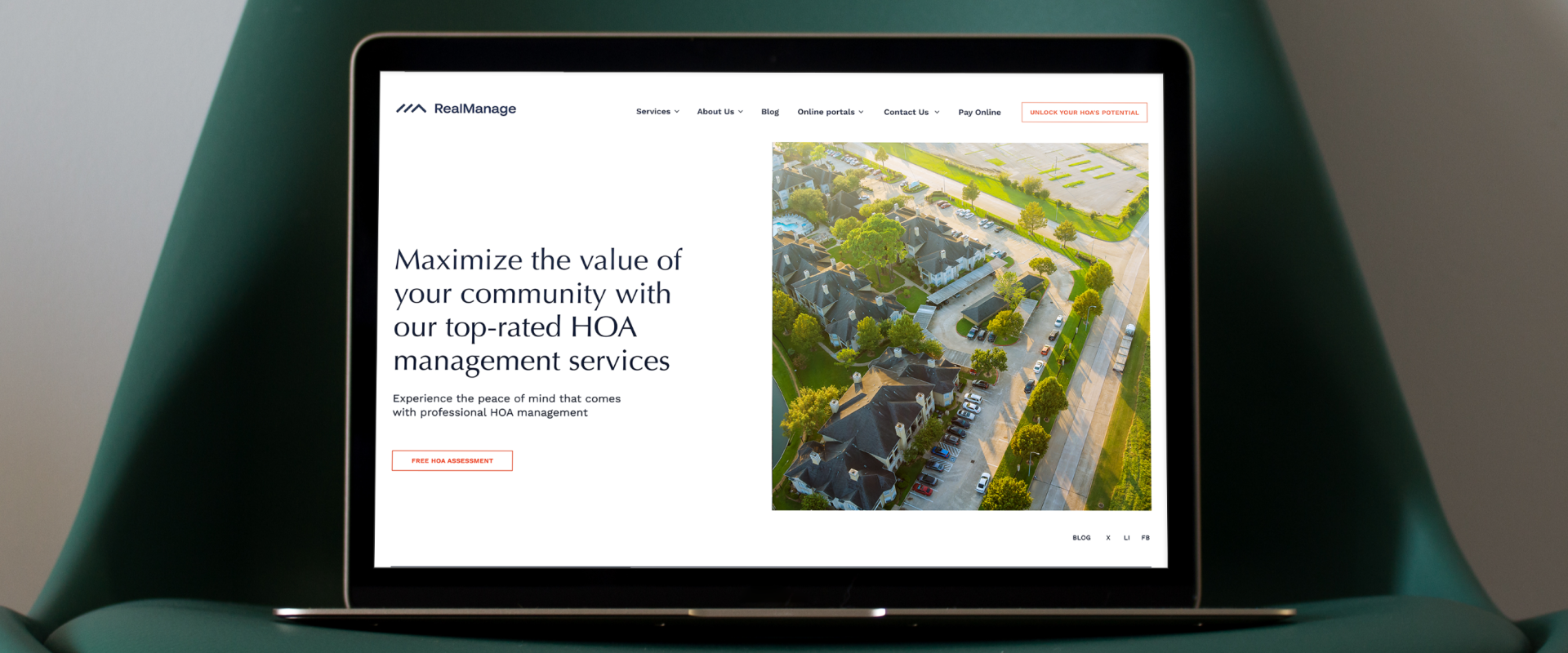 A laptop on a green chair displays a website for SaaS-based HOA management services, featuring a neighborhood aerial photo and promotional text that highlights streamlined property management solutions.