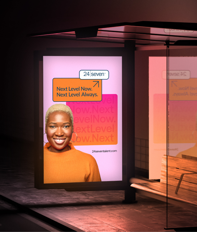A bus stop advertisement shows a smiling person in an orange sweater with text reading "Next Level Now. Next Level Always." Celebrating 25 years of next-level success, the 24 Seven logo is proudly displayed.