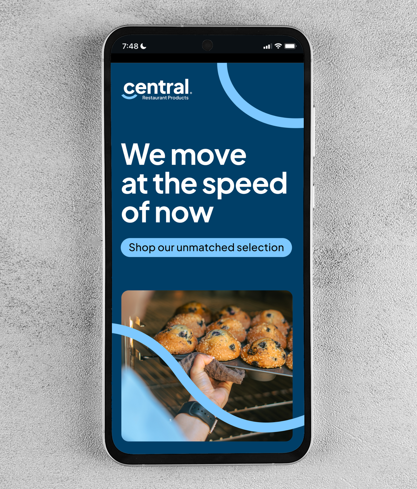 A smartphone displays a Central Restaurant Products ad—one of the TAKKT Foodservices brands—with the slogan "We move at the speed of now" and an image of a hand placing a tray of muffins in an oven.