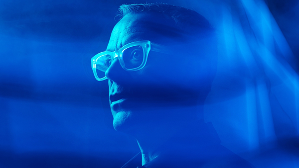 Person wearing glasses viewed through swirling blue light. The image, reminiscent of visuals created by advanced AI Image Generation Tools